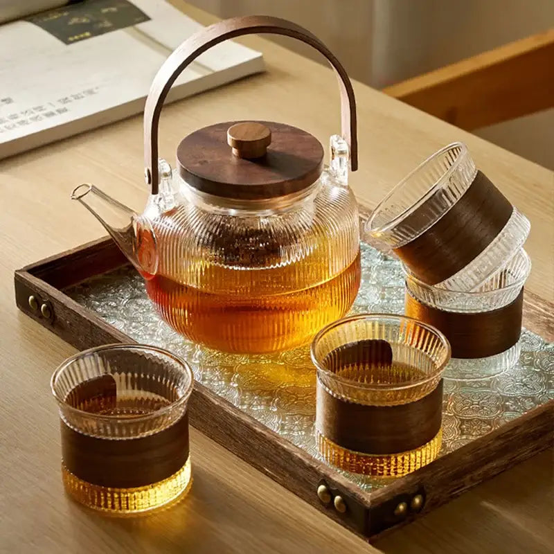 Clear glass tea pot with wooden lid and handle filled with amber tea from decorbites glass tea set
