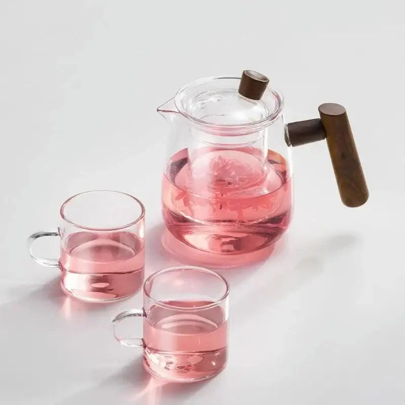 Clear glass tea pot filled with pink tea featuring a dark wood handle and lid knob from decorbites glass tea set