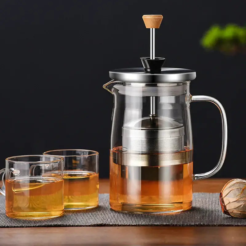 Clear glass french press tea set with stainless steel plunger wooden handle filled with amber tea decorbites glass tea