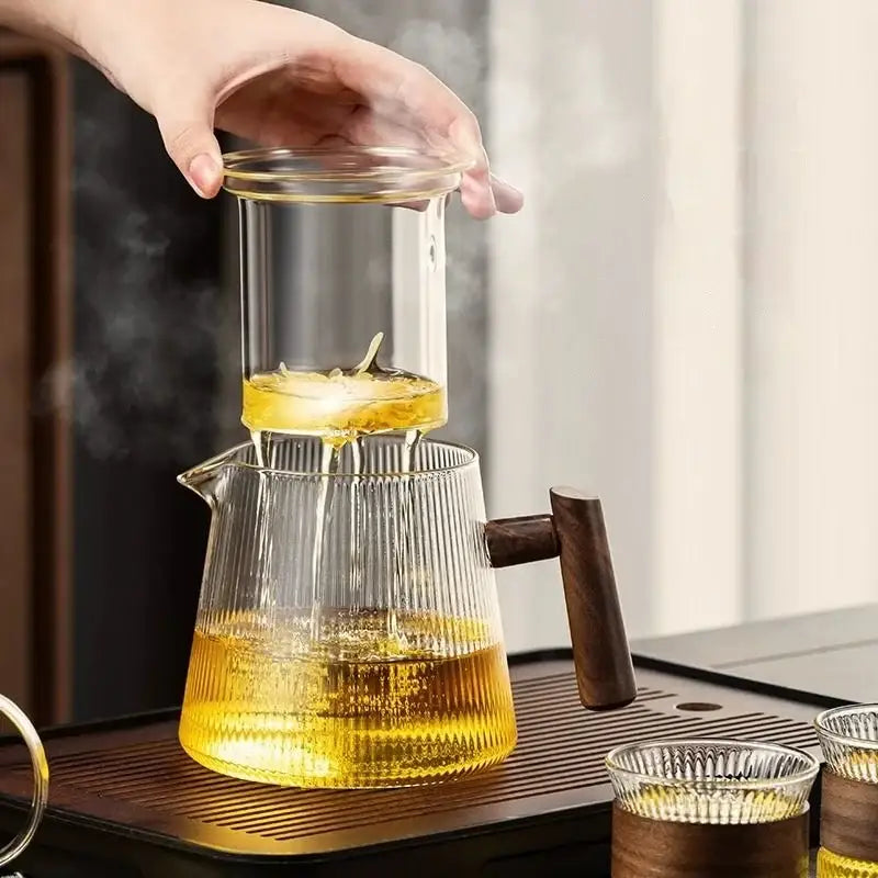 Clear glass decorbites glass teapot with wooden handle and vertical ridges filled with golden tea for home and restaurant brewing