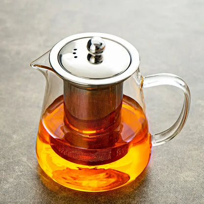 Clear glass teapot with stainless steel lid and built-in filter holding amber tea by DecorBites glass teapot