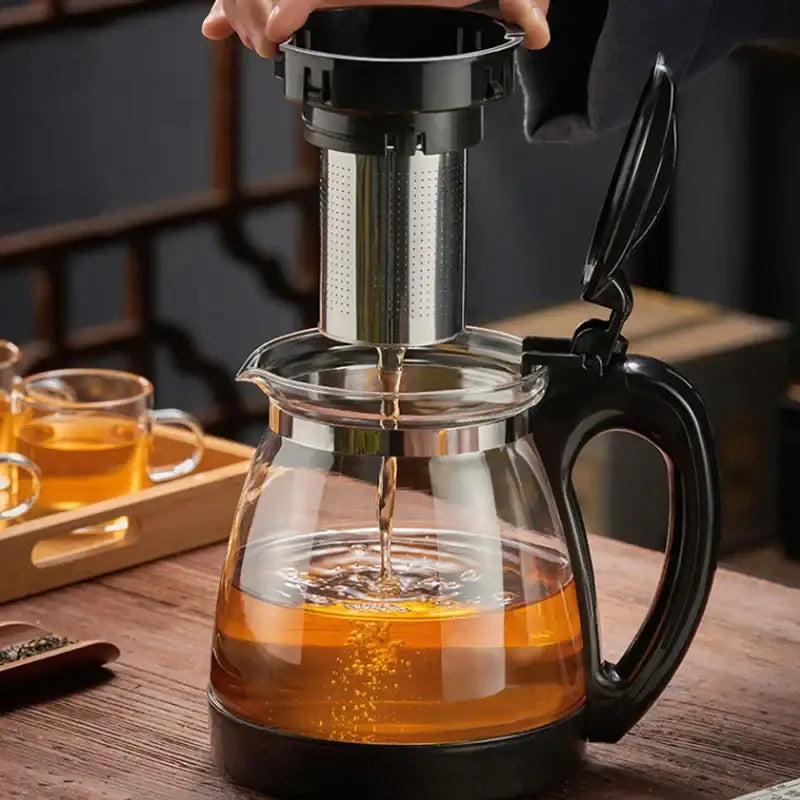 Clear glass teapot with black handle and base featuring stainless steel infuser draining tea in decorbites glass teapot