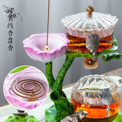 Pink lotus-shaped glass tea infuser with gold coil holder on green base for DecorBites lazy tea infuser set