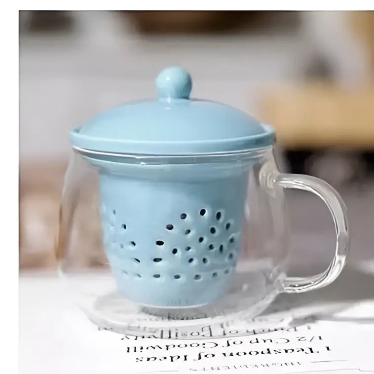 Light blue ceramic filter nestled inside a clear glass mug from decorbites glass teapot set for puer tea infusion