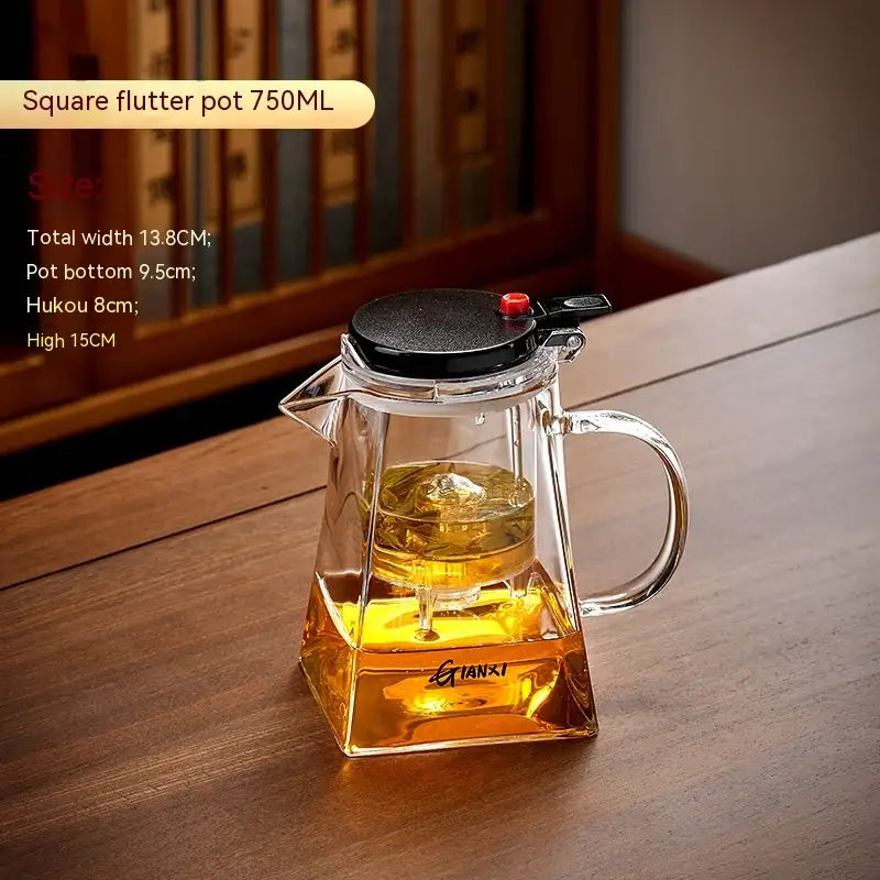 Clear glass square flutter pot with black lid and red knob containing golden tea in decorbites glass teapot set