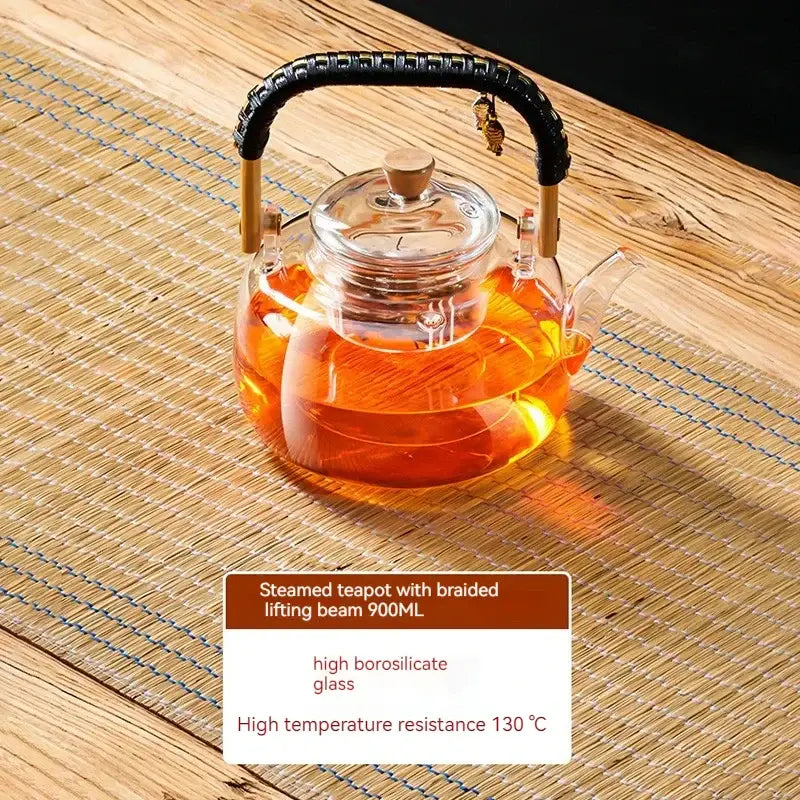Clear glass tea pot with black braided handle and wooden accents filled with amber tea from decorbites glass teapot