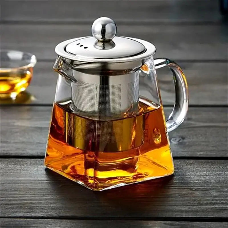 Clear glass DecorBites™ teapot with stainless steel infuser and lid filled with amber tea