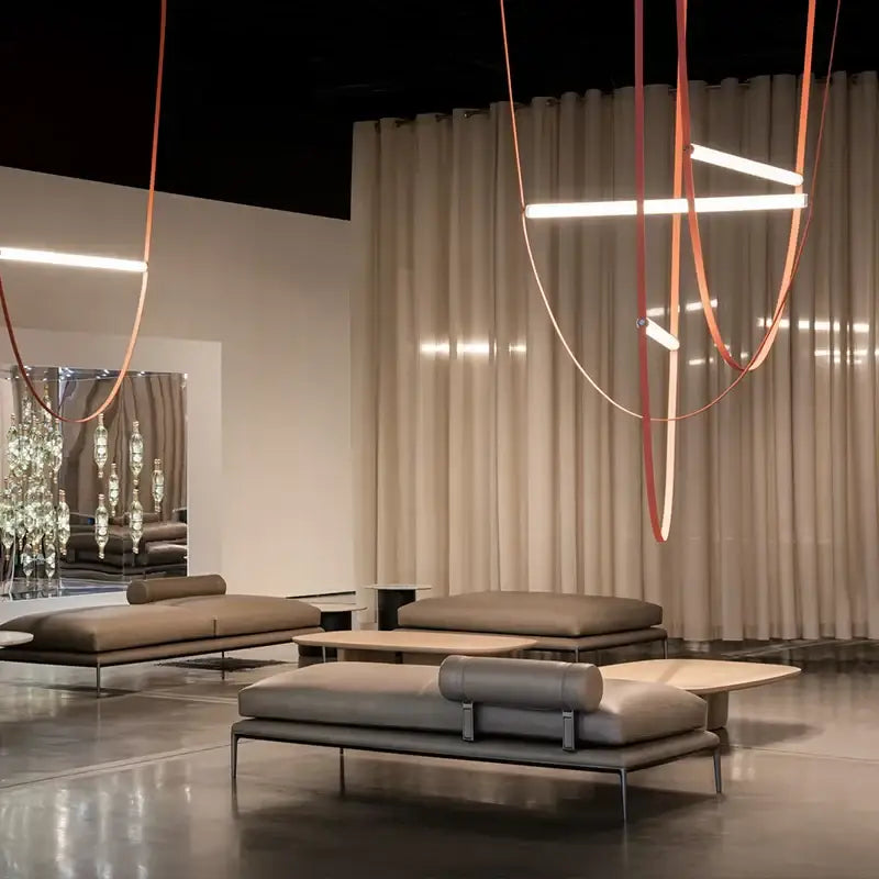 Modern taupe leather lounge sofa with minimalist metal frame shown alongside decorbites glass tube pendant light installation