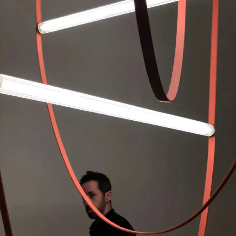 DecorBites glass tube pendant light with intersecting white fluorescent tubes and curved orange ribbons for modern decor