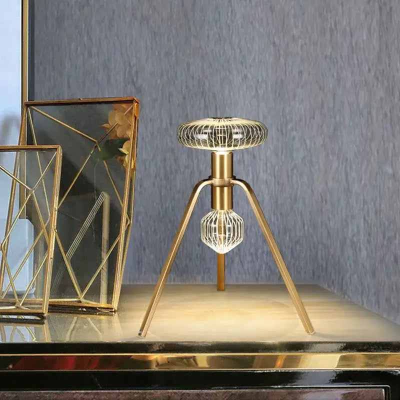 Gold-toned tripod table lamp with geometric wireframe and illuminated spheres in decorbites glass tubes pendant lamp design