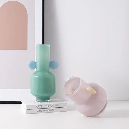 A mint green decorbites glass vase with two light blue spherical handles for floral arrangement accessory