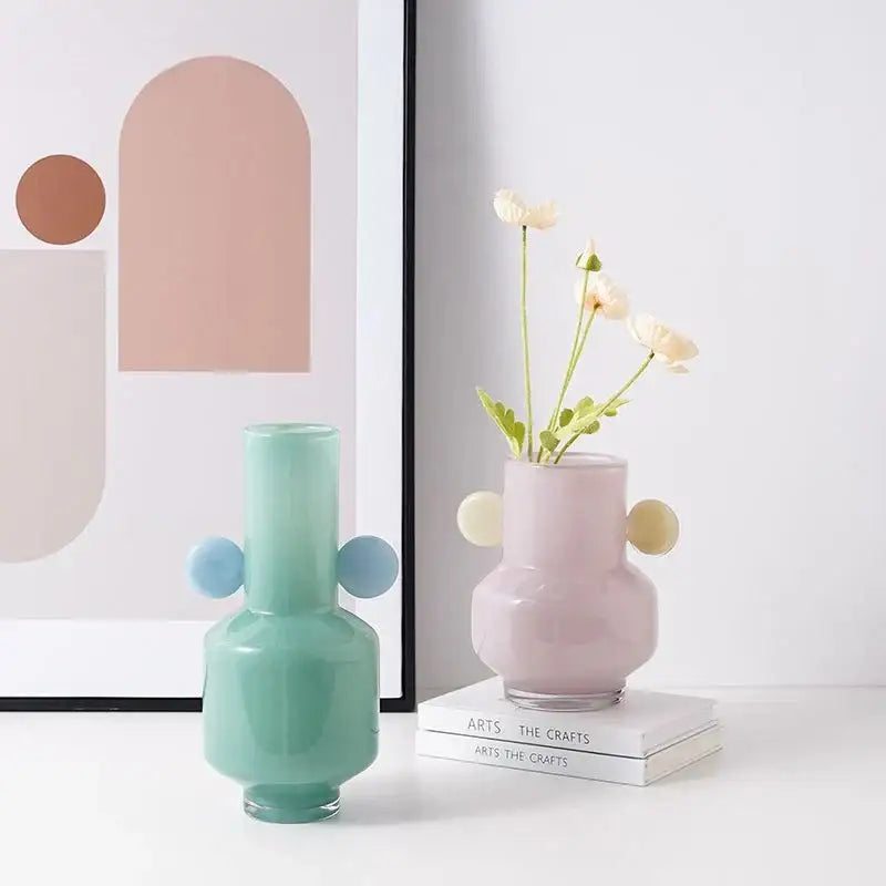 Pastel pink decorbites glass vase with rounded bulbous sides and two light yellow spherical handles for floral arrangement