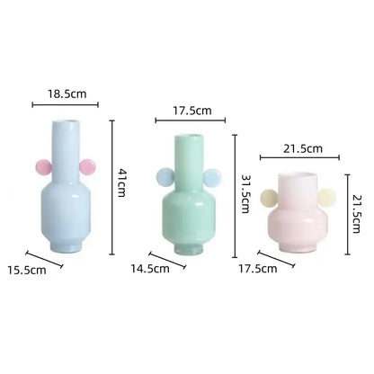 Pastel-colored decorbites glass vase with rounded body, slender neck, and soft pink and light blue spherical handles for floral arrangement