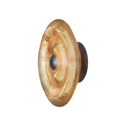 Golden decorbites glass wall lamp with concentrically ridged glass and dark metal backplate for modern living room lighting
