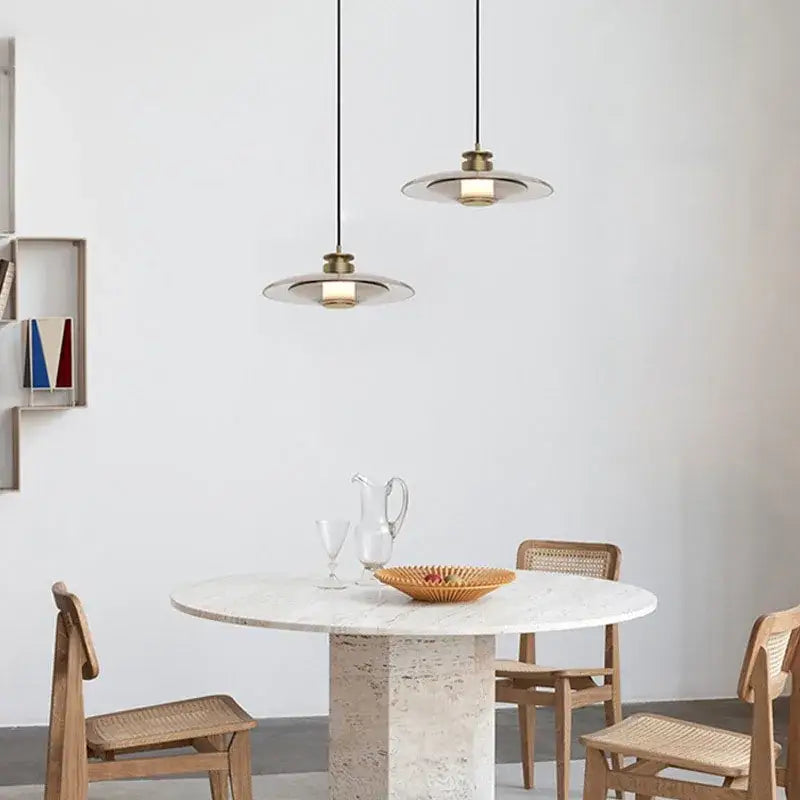 Two minimalist decorbites glass wall lamps with brass fixtures and translucent disc shades above a marble table