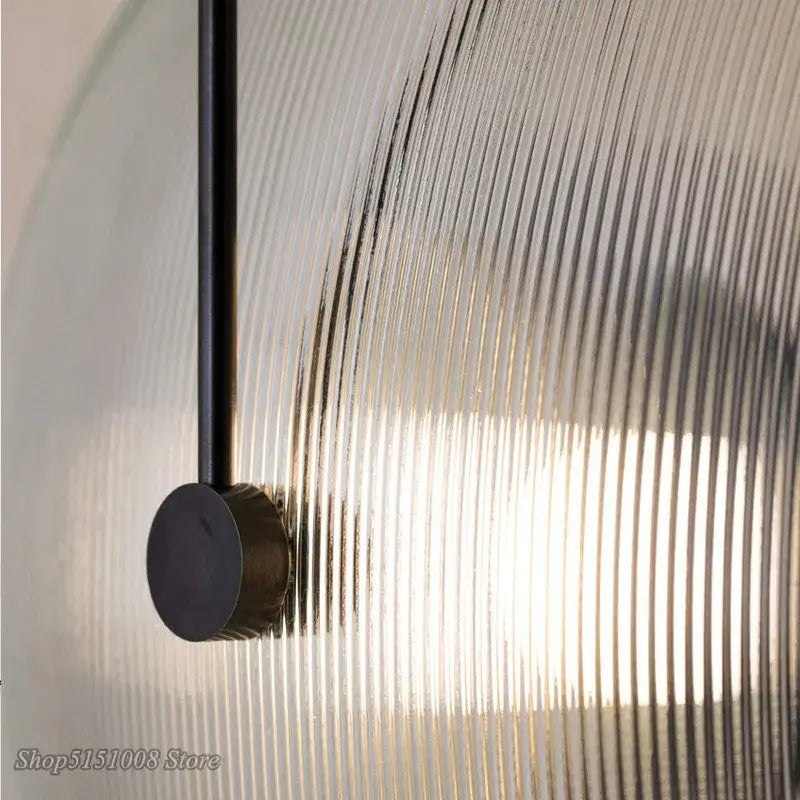 A modern decorbites glass wall lamp with a curved translucent glass shade and black metal rod suspension