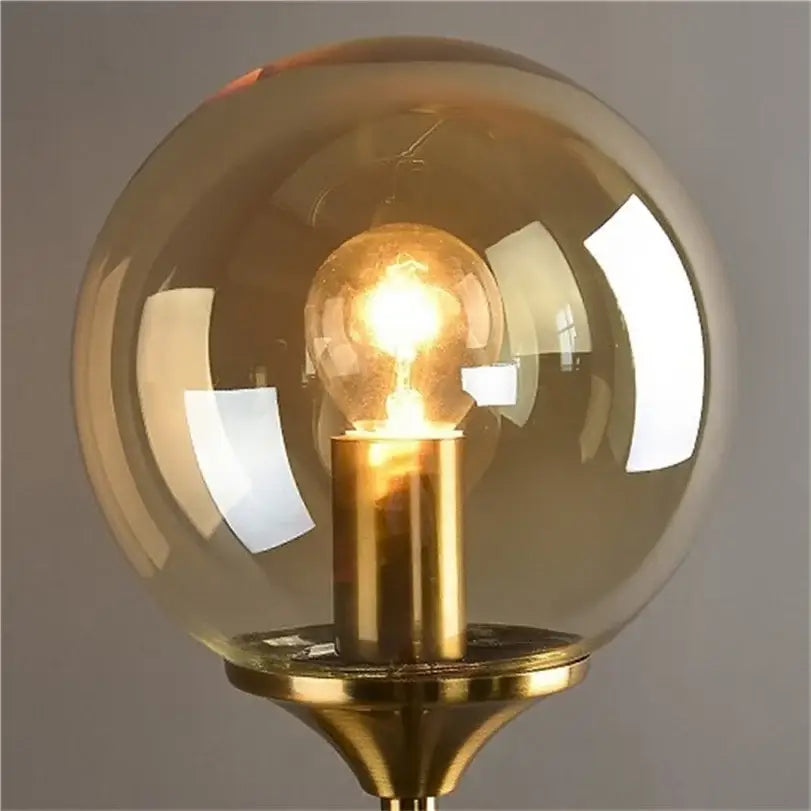 Decorbites glass wall lamp with warm amber globe, brass base, and exposed filament bulb for bedroom lighting