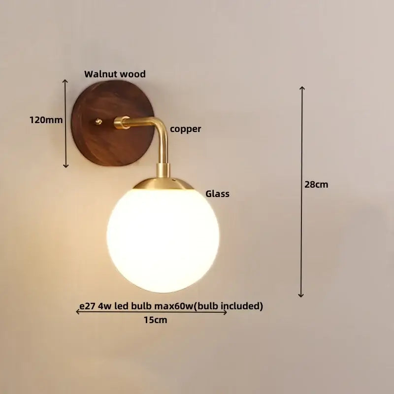 A modern decorbites glass wall light fixture with a walnut wood backplate copper arm and frosted glass globe