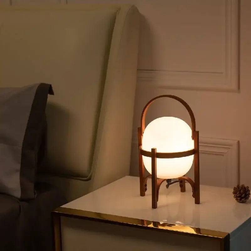 Warmly glowing DecorBites glass and wood metal table lamp with opaque white globe and minimalist wooden frame handle
