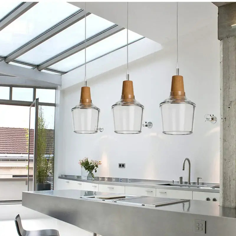 Three decorbites glass pendant lights with clear shades and warm-toned wood pendant light tops for modern gray decor
