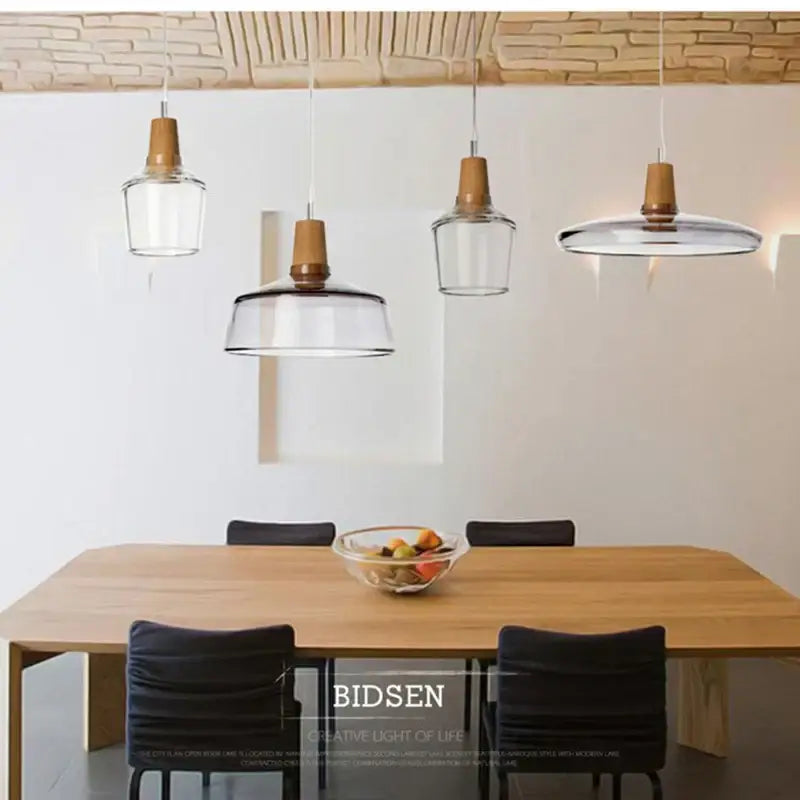 Clear glass DecorBites glass pendant light with wooden accents hangs above dining table in modern Nordic style