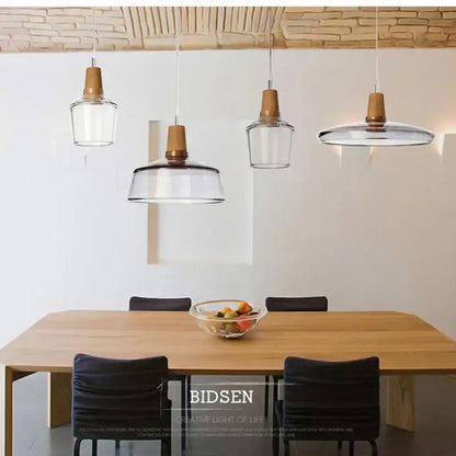 Clear glass DecorBites glass pendant light with wooden accents hangs above dining table in modern Nordic style