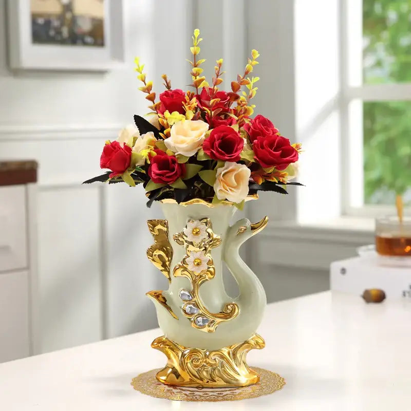 Elegant light green ceramic gold glass vase with gold ornate detailing holding red cream and yellow artificial roses