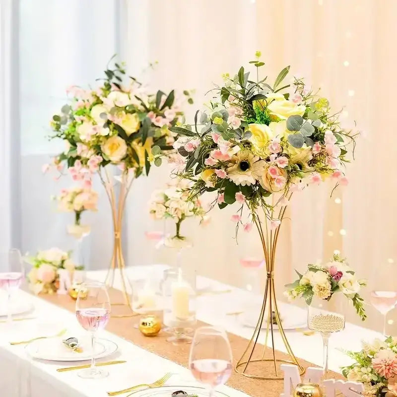 Elegant gold-toned iron flower vases with tall legs and cascading pink and yellow roses for wedding decor by DecorBites™