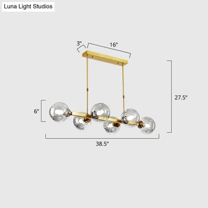 Gold-toned decorbites™ hand-blown dimpled glass island pendant lamp with five clear globe bulbs and rectangular ceiling mount