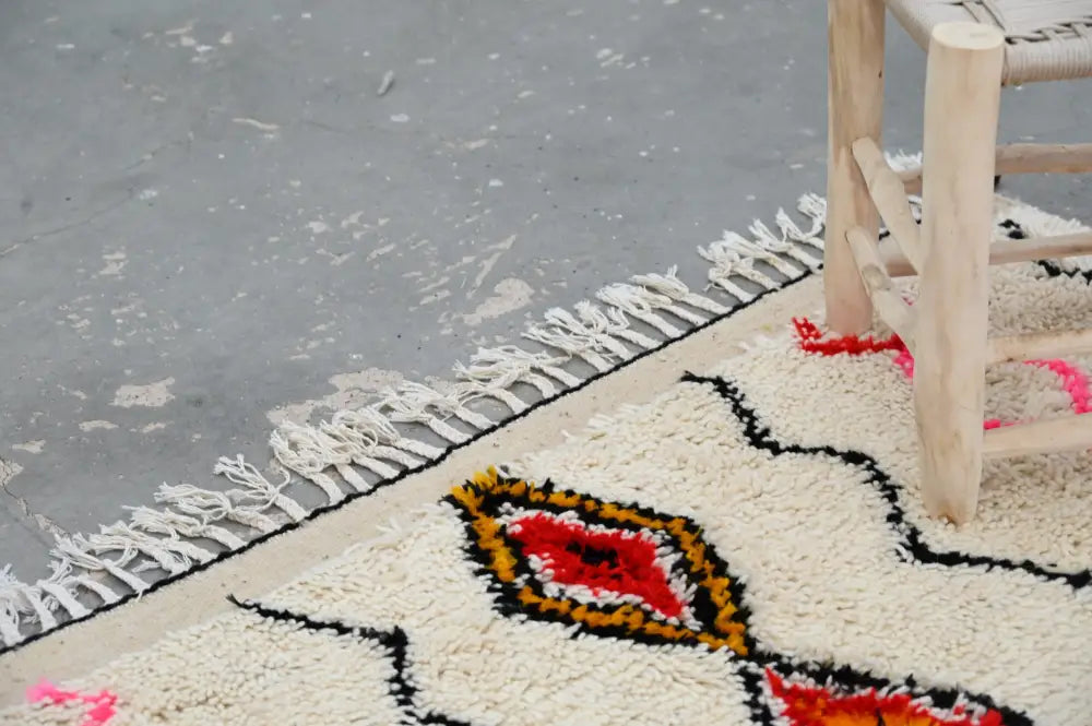 Cream-colored decorbites™ handmade azilal rug 240x150cm with bold red black orange geometric patterns and natural wool fringe