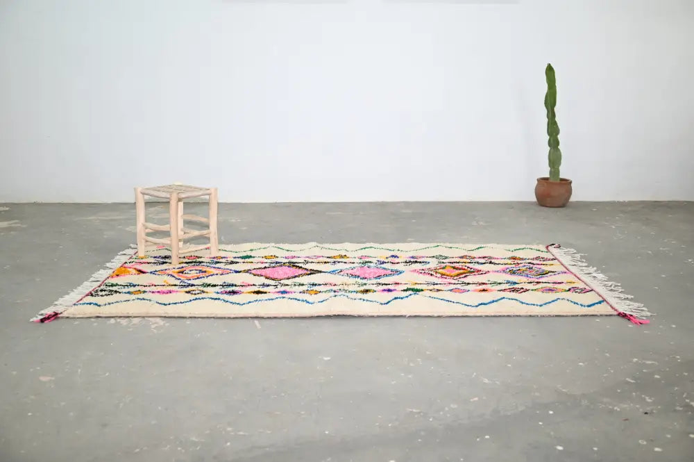 Beige handmade moroccan azilal rug with vibrant pink orange and blue geometric patterns 243x131 cm by decorbites