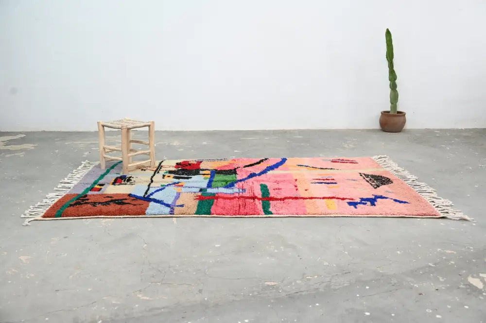 A vibrant handmade moroccan azilal rug with a geometric pattern in pink orange blue and green 244x147 cm