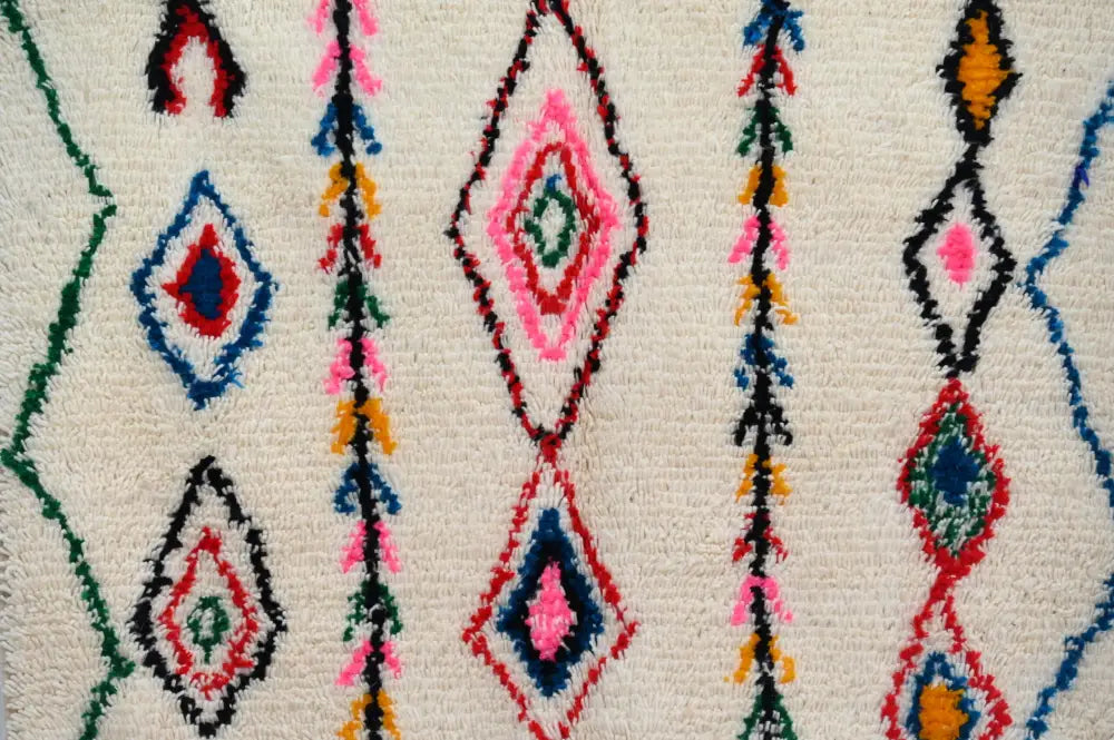 Vibrant moroccan handmade azilal rug with diamond and stripe patterns in pink blue red green yellow on natural wool cream base