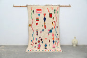 Cream-colored handmade moroccan azilal rug with vibrant pink blue green and red geometric patterns 247x141 cm