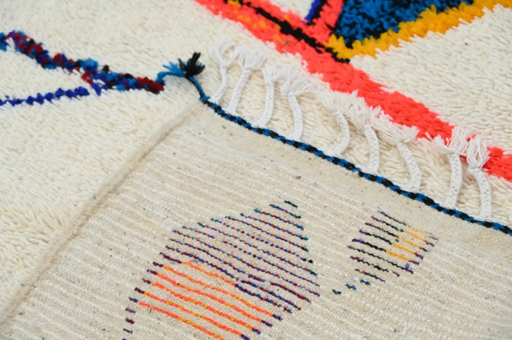 Cream-colored decorbites™ handmade traditional azilal rug with vibrant geometric patterns and white fringe 250x145 cm