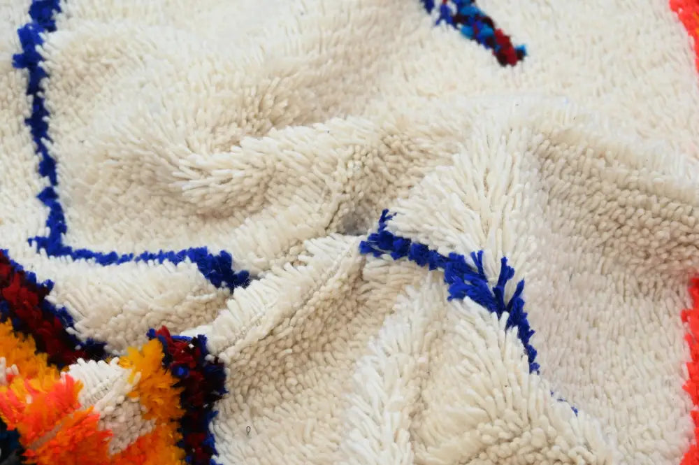 Cream-colored plush wool azilal rug with bold blue and orange geometric patterns handmade traditional azilal rug