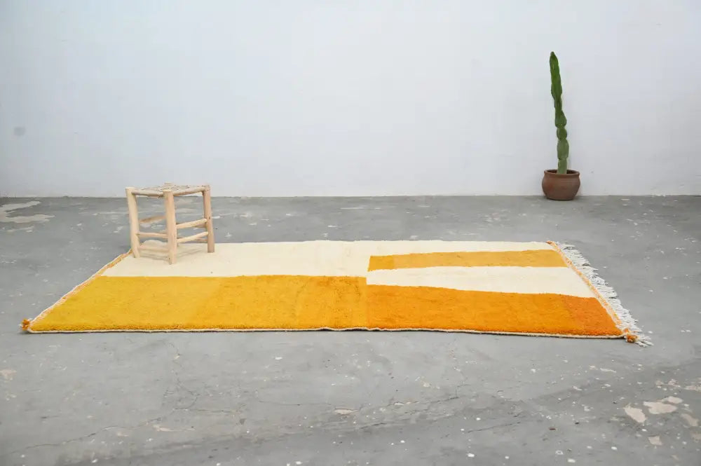 A vibrant yellow and cream moroccan handmade azilal rug with textured hand-knotted design and fringed edges by decorbites