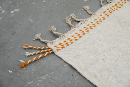Cream-colored handmade Moroccan azilal rug with orange dot pattern and twisted white and orange rope tassels 291x200cm