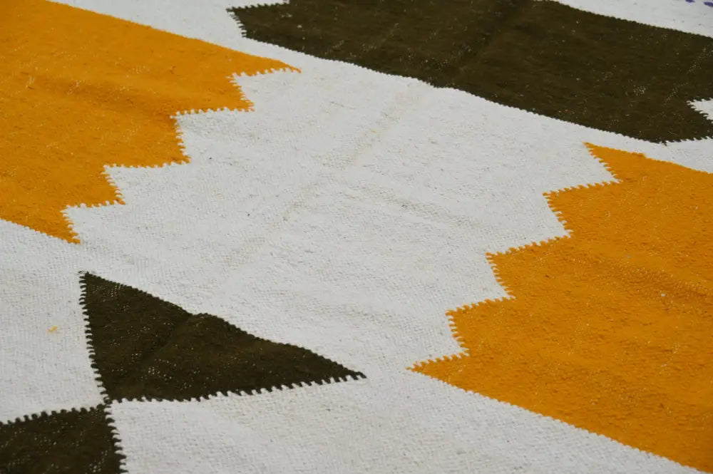 Vibrant moroccan handmade azilal rug with bold mustard yellow and olive green zigzag patterns on white woven textile