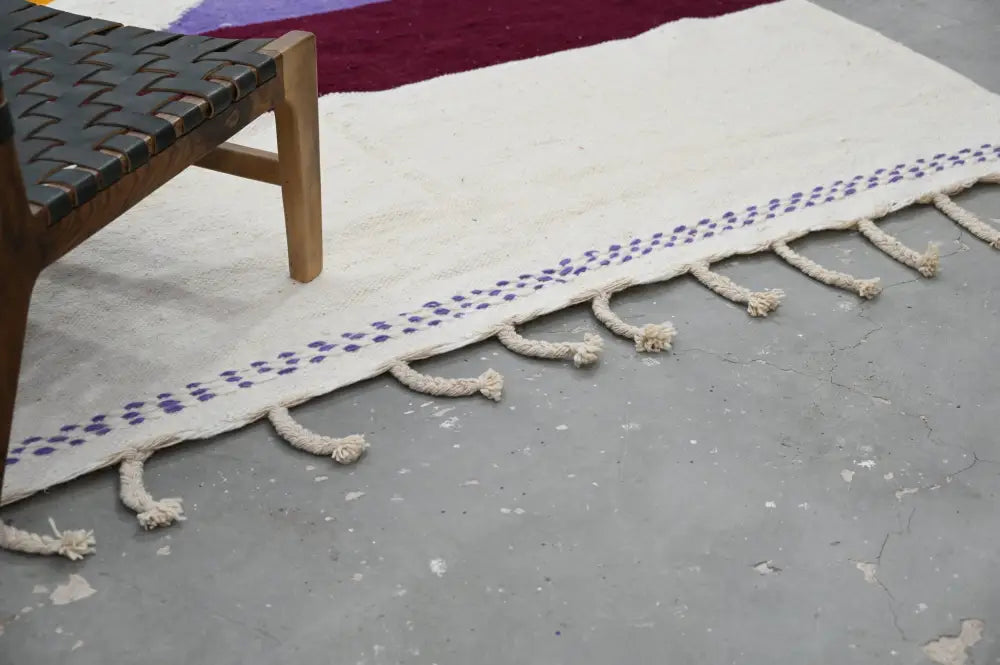 Cream-colored moroccan handmade traditional azilal rug with purple dot border and natural fiber tassels 304 x 202 cm