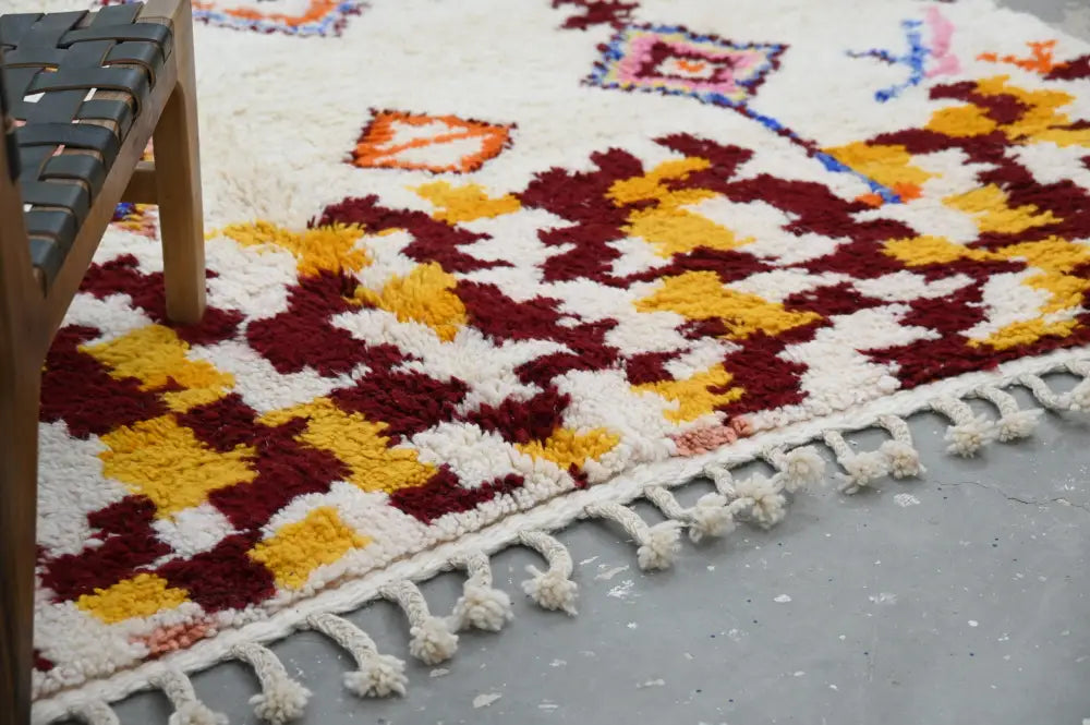 DecorBites™ handmade Moroccan Azilal rug with vibrant maroon and mustard geometric pattern on cream background with tassels
