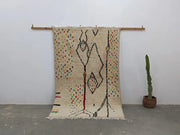 Cream-colored handwoven moroccan azilal rug with intricate black red geometric patterns and multicolored dots 234x147 cm