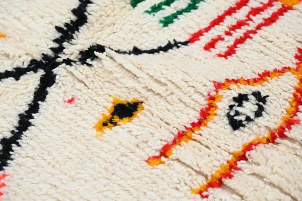 Cream-colored handwoven moroccan azilal rug with bold black red green and orange geometric patterns 245x146 cm