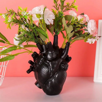 Black anatomically detailed heart shape resin vase by DecorBites holding artificial white and pink flowers