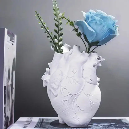 White DecorBites heart shape resin vase with detailed vein carvings holding a light blue rose and greenery