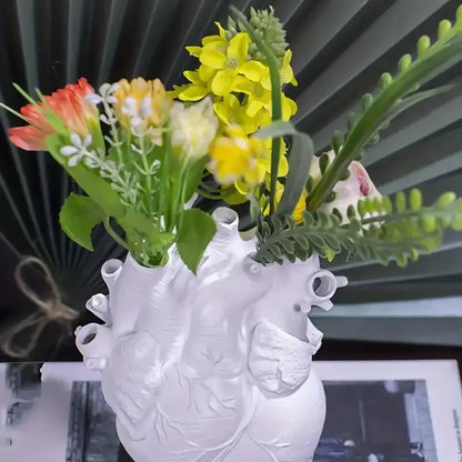 DecorBites™ white heart shape resin vase holding yellow orange and white artificial flowers in vibrant bouquet