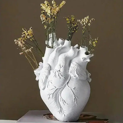 White ceramic DecorBites™ heart shape resin vase with detailed anatomy holding dried yellow and white flowers