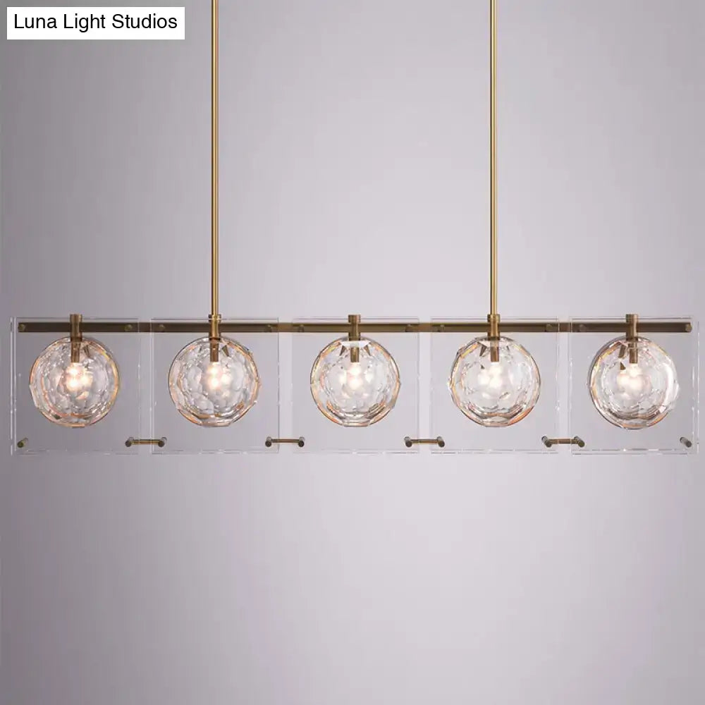 Modern five-light island light fixture with brass finish and clear faceted glass ball globes by decorbites