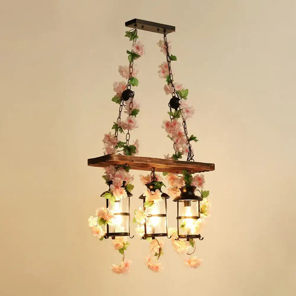 A rustic wooden cage island pendant light with black metal lanterns and pink plant decoration for restaurant lighting