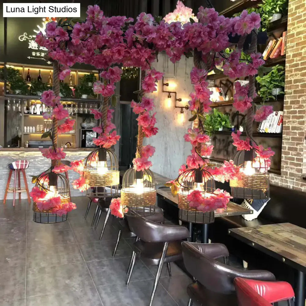 Pink artificial cherry blossoms frame ornate black industrial metal ceiling lamp birdcage pendant fixture height